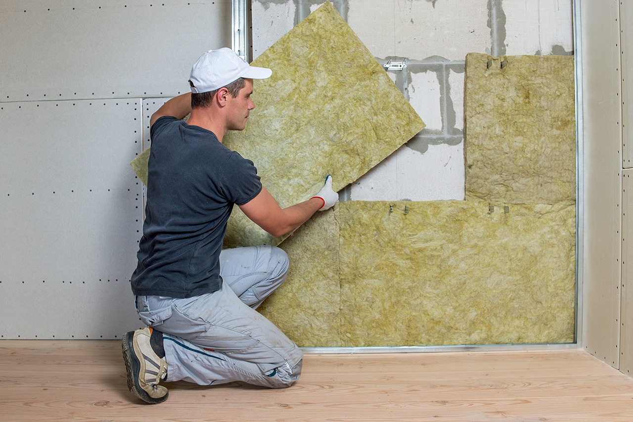worker insulating a room wall with mineral rock wool thermal ins